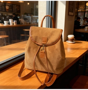 Gros plan d'un sac à dos en daim caramel avec cordon en cuir sur un comptoir en bois