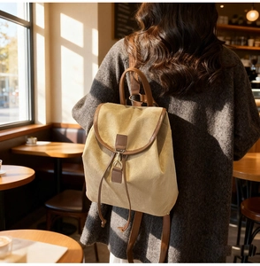 Femme portant un sac à dos de voyage en toile beige avec sangles marron dans un café ensoleillé