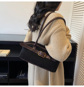 Détail du sac bandoulière en suède avec lanières en cuir marron et boucle dorée sur modèle