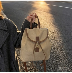 Détail d'un sac à dos en daim beige avec bordures en cuir marron et boucle dorée