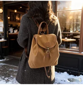 Détail d'un sac à dos en daim caramel avec finitions en cuir et fermoir métallique