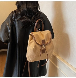 Vue arrière d'un sac à dos vintage kaki avec détails en cuir marron porté par une femme