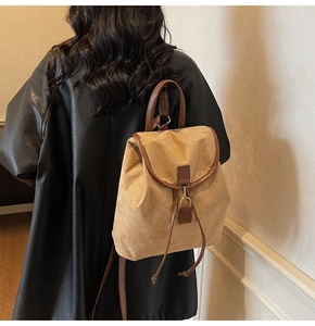 Détail du sac à dos vintage en daim camel avec finitions en cuir marron porté par un mannequin
