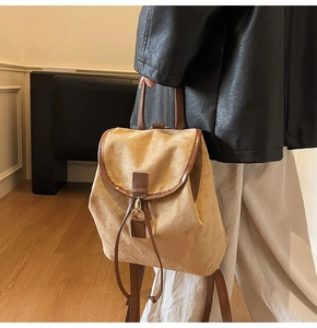Détail d'un sac à dos en daim kaki avec garniture en cuir brun tenu par un mannequin