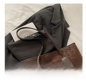 Close-up of leopard print tote bag texture and soft carrying handles on a suit