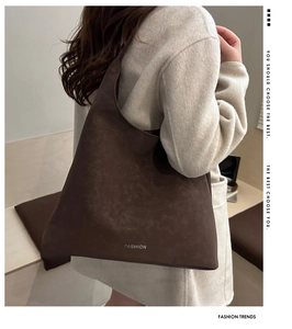 Détail du grand sac cabas en daim marron foncé avec inscription fashion sur un manteau