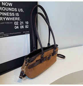 Détail du sac à bandoulière en daim marron avec lanières en cuir et boucle dorée
