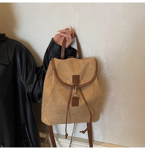 Détail d'un sac à dos en daim kaki avec bordures en cuir marron et boucle métallique