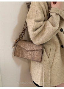 Close-up of retro bronze crossbody bag with brushed texture on wool coat background