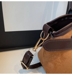 Détail du sac à bandoulière en daim marron avec garniture en cuir et boucle dorée