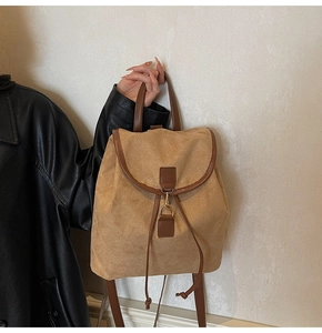 Gros plan du sac à dos en daim kaki avec finitions en cuir marron et boucle en métal