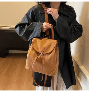 Détail d'un sac à dos vintage en velours marron avec lanières en cuir et boucle métal