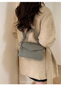 Detail of grey-green textured handbag with knotted handles and minimalist retro design
