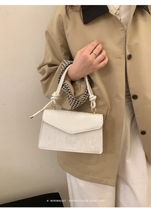 Detail of white jacquard envelope bag with knotted handle and elegant retro texture