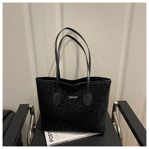 Detailopname van de zwarte tote bag met luipaardreliëf en dubbele dunne schouderbanden