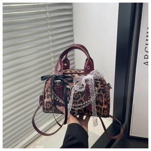 Detail of leopard print handbag featuring red leather trim, lace edging, and metal chains