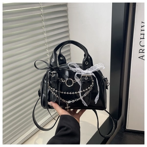 Detail of gothic punk style black bag with silver chains and white lace bow decoration