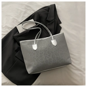Gros plan d'un sac cabas léopard gris avec anses argentées sur un blazer chic