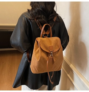 Détail d'un sac à dos en daim marron avec rabat rétro et finitions de sangles en cuir