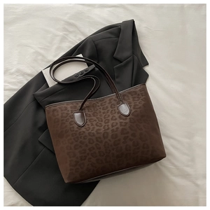 Détail du sac cabas léopard avec poignées en cuir marron sur un blazer noir
