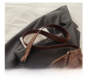 Detail view of coffee leopard print bag with tassels and wide strap on white bedding