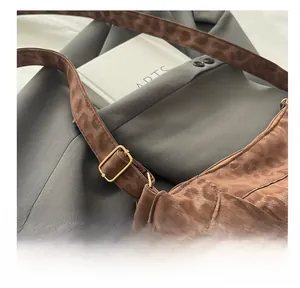 Detail of adjustable gold buckle on a brown leopard print shoulder bag with fringe