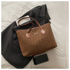 Détail du sac cabas léopard avec texte FASHION sur un fond texturé blanc épuré