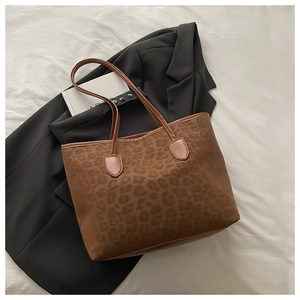Détails de la texture léopard du sac cabas posé sur un blazer noir pour look de bureau