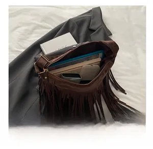 Macro view of brown suede fringe bag showing large capacity for books and tablet