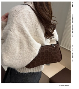 Detail view of brown leopard print suede baguette bag worn with an ivory sweater