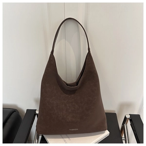 Dettaglio borsa tote vintage in pelle marrone con logo argento su sfondo bianco puro