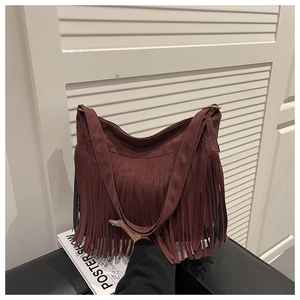 Detail of burgundy fringe shoulder bag showing suede texture and metal strap buckle