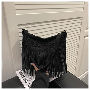 Close-up of black suede fringe shoulder bag with subtle leopard print and boho details