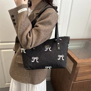 Quilted tote bag with colorful embroidered bows and elegant brand plaque detail