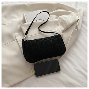 Détail du mini sac en velours noir à imprimé léopard sombre sur un blazer blanc