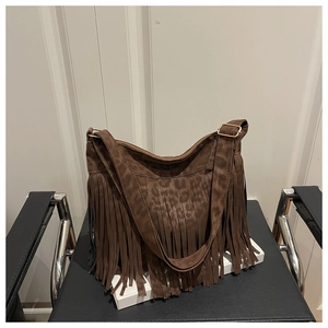 Detail of bohemian brown suede shoulder bag with leopard print and fringe accents