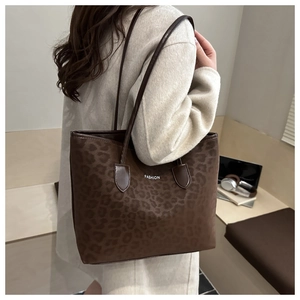 Grand sac cabas léopard avec lettrage blanc et anses en cuir porté avec un manteau beige