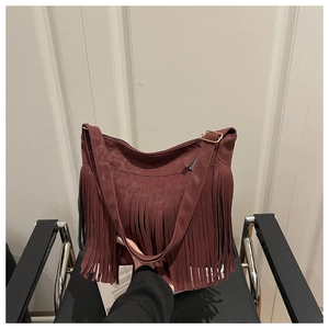 Detail of burgundy suede tote bag featuring long bohemian tassels and golden metal buckle