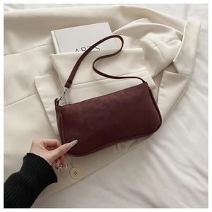Gros plan du sac baguette rouge mat avec crochets en métal sur un fond blanc neutre