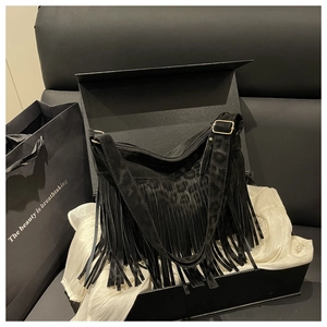 Close-up of black fringe shoulder bag with leopard pattern texture in a gift box