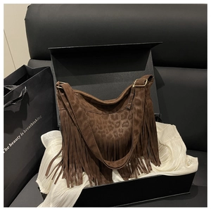 Detail of vintage brown suede crossbody bag featuring leopard embossing and fringe tassels