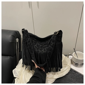 Detail of black leopard print tote bag featuring long fringes and gold metal hardware