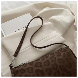Détail d'un sac d'épaule vintage à motif léopard posé sur un blazer crème élégant