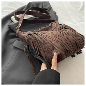 Detail of a brown suede crossbody bag with long fringes and leopard print strap