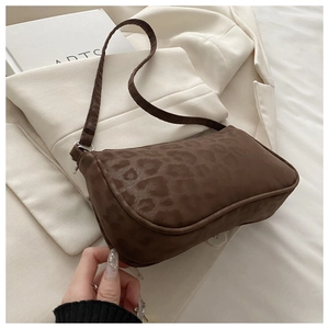 Détail du sac sous le bras à motif léopard marron posé sur un blazer beige