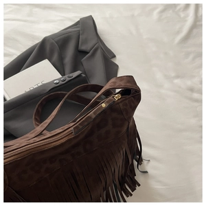 Detail of leopard print suede shoulder bag with long fringes and golden zipper