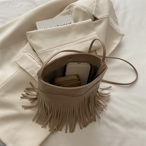 Minimalist khaki fringe bucket bag with matte leather and long tassels in a scene