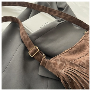 Detail of leopard print crossbody bag with stylish fringe and golden buckle