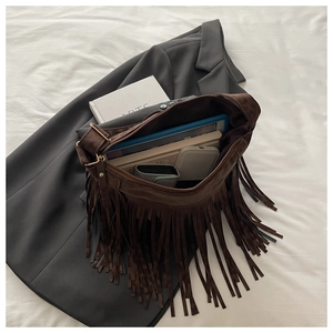 Detail of dark brown suede shoulder bag with long fringes and large interior capacity
