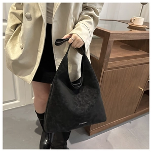 Dettaglio della borsa tote in pelle scamosciata nera con logo e trama del materiale